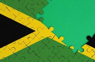 le drapeau de la jamaïque est représenté sur un puzzle terminé avec un espace de copie vert gratuit sur le côté droit photo