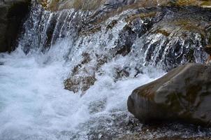 image en gros plan d'une petite cascade sauvage sous forme de courts jets d'eau entre des pierres de montagne photo