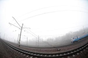 le train de banlieue ukrainien se précipite le long de la voie ferrée par un matin brumeux. photo fisheye avec distorsion accrue