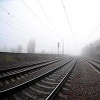 la voie ferrée par un matin brumeux. beaucoup de rails et de traverses vont dans l'horizon brumeux. photo fisheye avec distorsion accrue