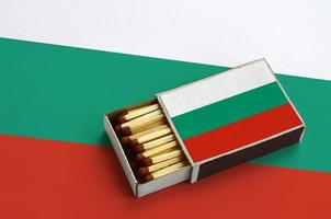 le drapeau de la bulgarie est affiché dans une boîte d'allumettes ouverte, qui est remplie d'allumettes et repose sur un grand drapeau photo