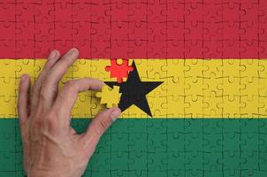 le drapeau du ghana est représenté sur un puzzle, que la main de l'homme complète pour se plier photo