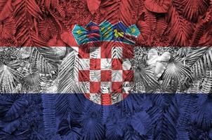 drapeau croatie représenté sur de nombreuses feuilles de palmiers monstera. toile de fond à la mode photo