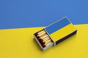 le drapeau de l'ukraine est affiché dans une boîte d'allumettes ouverte, qui est remplie d'allumettes et repose sur un grand drapeau photo