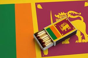 le drapeau du sri lanka est affiché dans une boîte d'allumettes ouverte, qui est remplie d'allumettes et repose sur un grand drapeau photo