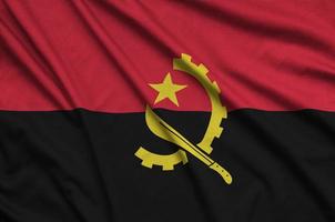 le drapeau angola est représenté sur un tissu de sport avec de nombreux plis. bannière de l'équipe sportive photo
