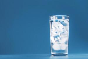 verre avec de l'eau et des glaçons sur fond bleu photo