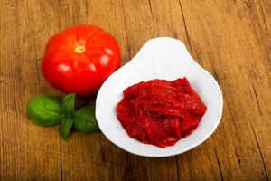 pâte de tomate dans un bol sur fond de bois photo