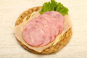 tranches de saucisse sur planche de bois et fond de bois photo