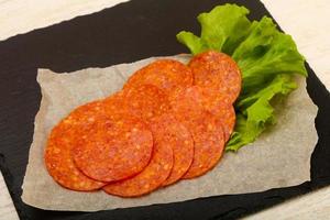 Saucisse au pepperoni sur planche de bois et fond de bois photo