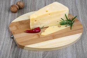 Fromage jaune sur planche de bois et fond de bois photo