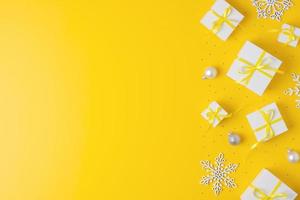 décorations de noël avec des cadeaux d'emballage et des boules sur fond jaune. mise à plat, espace de copie photo