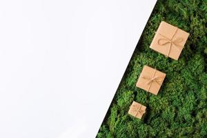 fond naturel de noël avec de la mousse verte et des cadeaux emballés dans du papier kraft. mise à plat, espace de copie photo