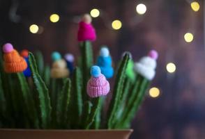 des chapeaux décoratifs en laine multicolores avec des pompons sont portés sur les tiges d'un cactus vivant dans un pot à la maison. drôle et créatif. notion d'hiver. photo