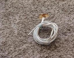 fil blanc torsadé épais qui sortait du mur. une bobine de câble électrique sur un mur gris. photo