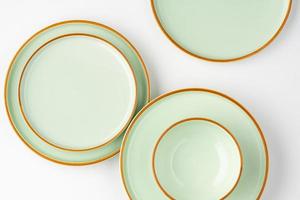 un ensemble de vaisselle en céramique vert pastel aux contours orange. vue de dessus photo