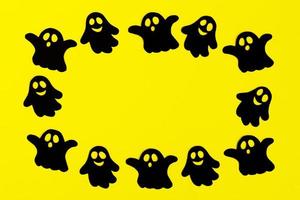 cadre de fantômes de papier noir sur fond jaune. décorations de vacances pour halloween avec espace de copie. photo
