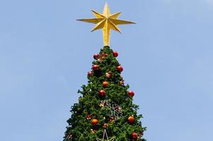 l'ornement étoile met au sommet du grand sapin de noël avec des boules colorées et d'autres ornements. photo