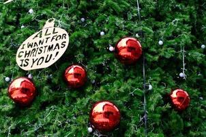 boule rouge et autre ornement avec mot tout ce que je veux pour noël c'est que tu décores sur le sapin de noël photo