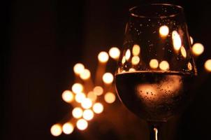 un verre de vin a l'ombre d'une lumière bokeh jaune et orange qui est isolée sur un fond de couleur sombre photo