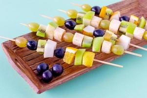 ensemble de canapés aux fruits, baies sur plaque de bois sur fond bleu photo