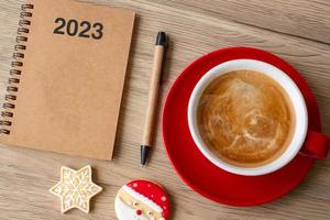 Objectif 2023 avec carnet, tasse à café, biscuits de noël et stylo sur table en bois. noël, bonne année, résolution, liste de choses à faire, concept de stratégie et de plan photo