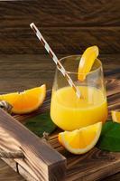 jus d'orange frais dans des verres avec des oranges coupées sur un plateau en bois. nature morte rustique aux agrumes photo