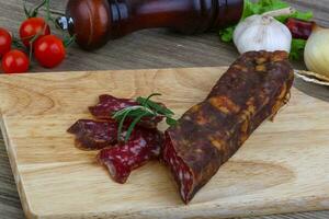 saucisse de salami sur planche de bois et fond de bois photo