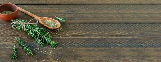 romarin lié sur une planche de bois avec des herbes et des graines séchées photo