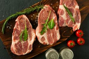 viande crue de cou de porc pour les steaks frais sur une planche à découper en bois. vue de dessus. photo