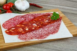 saucisse de salami sur planche de bois et fond de bois photo