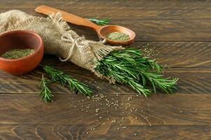 romarin lié sur une planche de bois avec des herbes et des graines séchées photo