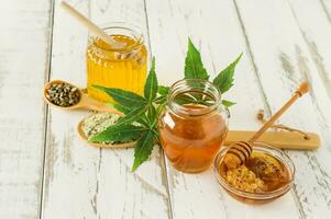 miel biologique frais avec des feuilles et des graines de cannabis plus profondes et sur une table en bois. alimentation saine médecine alternative photo
