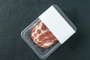 steak de porc marbré cru dans un emballage sous vide sur fond noir, vue de dessus, maquette de logo pour la conception photo