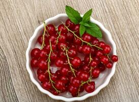 groseilles rouges dans un bol sur fond de bois photo