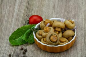 Champignon mariné dans un bol sur fond de bois photo