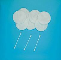 tampons de coton et cotons-tiges. un nuage de cotons et une pluie de cotons-tiges sur fond bleu. photo