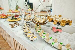 belle barre chocolatée de mariage avec des bonbons, des fruits et de la nourriture. table de banquet de mariage photo