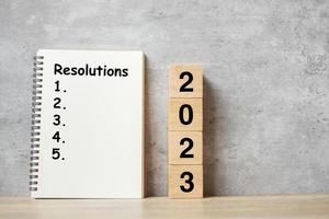 Bonne année 2023 avec carnet de résolution et numéro en bois. compte à rebours, objectifs, plan, action et concept de mission photo