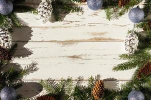 fond en bois blanc avec décoration de noël de branches d'épinette verte, cônes naturels et jouets de vacances. vue de dessus. une copie de l'espace. photo