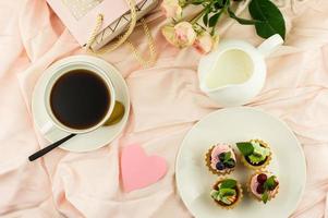 vue d'en haut pour un délicieux petit déjeuner au lit le jour de la saint valentin. tasse de café, cadeau, fleurs. photo