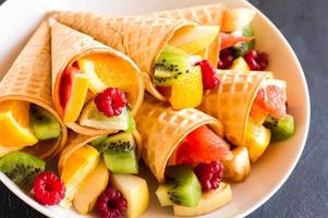 fruits mûrs juteux dans des cônes gaufrés sur une assiette blanche. angle rapproché. photo