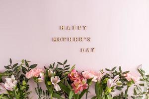 une composition festive, une affiche, une carte de fête des mères. une bordure de belles fleurs sur fond violet avec une inscription. vue de dessus. mise à plat. photo