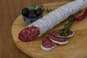 Saucisse fuet sur planche de bois et fond de bois photo