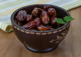 Dates fruits dans un bol sur fond de bois photo