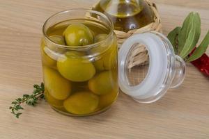 olives vertes dans une bouteille sur fond de bois photo