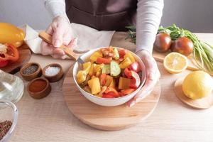 une délicieuse salade diététique bio de légumes frais dans un grand bol. la main de la jeune fille tient une fourchette avec des morceaux de laitue. photo