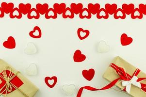 fond festif pour la saint valentin. décor de coeurs rouges, bougies en forme de coeur et coffrets cadeaux en papier craft. vue de dessus. mise à plat. photo