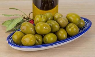 olives vertes dans un bol sur fond de bois photo
