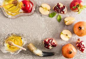 mise en page à plat, vue de dessus, fond de béton gris avec pommes, grenade, corne, miel dans un bol en argent. nouvel an rosh hashanah. photo